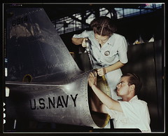 Mrs. Virginia Davis, a riveter in the assembly and repair department of the Naval air base, supervises Chas. Potter, a NYA trainee from Michigan, Corpus Christi, Texas. After eight weeks of training he will go into civil service. Should he be inducted or 