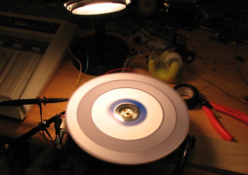 A light shines down onto a spinning disc, which has desgins printed on it in shades of gray.  The designs actually correspond to x and y coordinates for an image, which can be viewed using an oscilloscope.