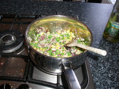 Vegetables and cummin added to the rice, coated with oil.