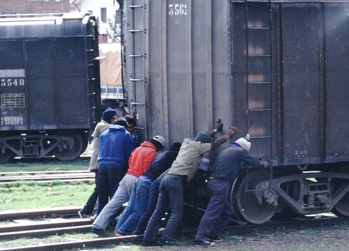 A group of men pushing a railway freight car