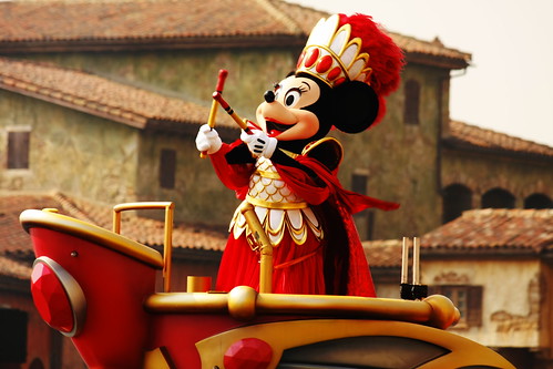Minnie, the Spirit of Love, is on top of her Griffon in a strong red outfit with the drum sticks.