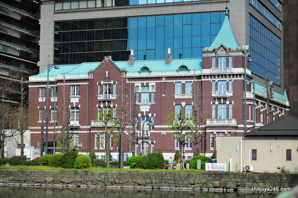 One of the many older buildings around Tokyo Station which as been preserved and incorporated into the development of a new taller building. Can you see the old building roof meeting the new glass building on the right side?