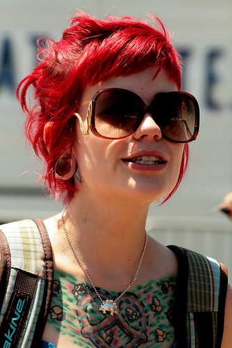 Red haired woman showing a large colorful heart tattoo on her chest
