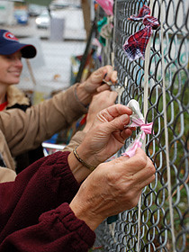 Judy Doll ties a symbolic ribbon at the 950 Main St. tent city. The ribbons spell Homes Now. 