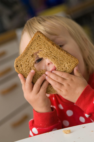 toddler peeking through a hole in whole-grain bread
