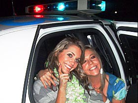 Two young women pose in an RCMP squad car at UBC July 1.