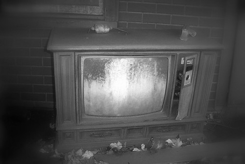 An old Zenith TV sits on the porch of an abandoned house...
