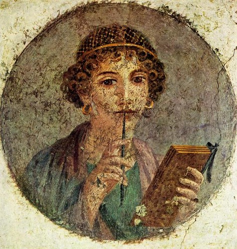 Pompeiian fresco of Sappho by an unknown artist, via laits.utexas.edu, which describes the fresco as: A young woman holding a stylus and a booklet of wax tablets. A gold hair net binds her hair and she wears large, gold earrings.