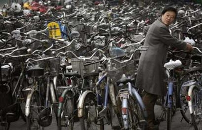 A woman collects her bicycle from a parking lot outside a subway station in Beijing