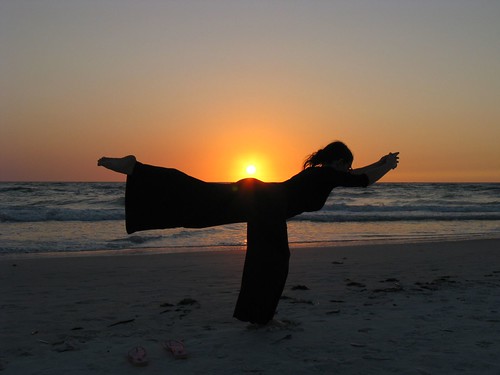 Silueta de una chica haciendo yoga en la playa al atardecer
