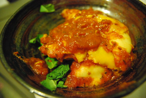 Pierogi in tomato sauce on spinach