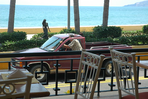 Mermaid watches a man push his broken down truck on the highway, from the Best Western hotel cafe, tables, chairs, place settings, Pacific Ocean, South Mazatlan, Sinaloa, Mexico by Wonderlane