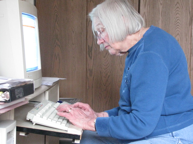 Photograph of a senior citizen working at a desktop computer