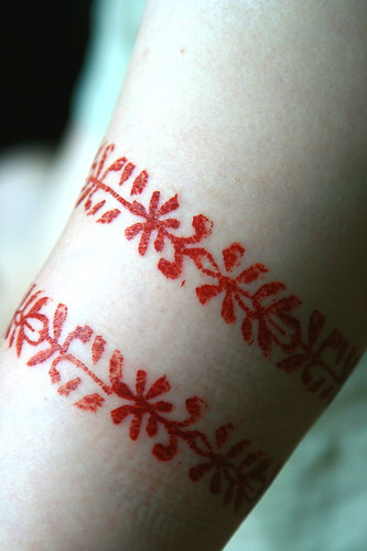 Red Tribal Ornament of Flower Tattoo on the Hand