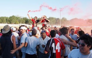 Matías Bendazzi es llevado en andas con los brazos en alto con humo rojo para desatar la alegría por un nuevo campeonato de Colón de Arroyo Cabral