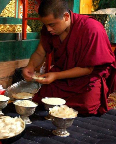 Tibetan Buddhist monk in maroon robes preparing the flower and rice symbolic offerings, silver ritual cups, Sakya Lamdre, Tharlam Monastery of Tibetan Buddhism, Boudha, Kathmandu, Nepal by Wonderlane
