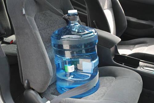 I strap the jug in like a passenger to keep it from moving around. Just make a loop with your seatbelt over the spout!