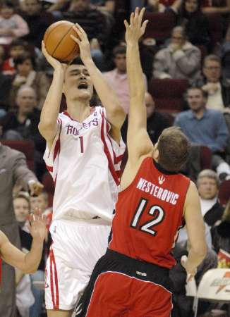Yao Ming double-pumps in mid-air over Toronto's Rasho Nesterovic before shooting the ball toward the basket, which bounced around the rim for a bucket in the fourth quarter.  Yao led the way in the fourth quarter with 8 big points, and would lead all scorers with 25 points on 8-of-19 shooting, and 9-of-9 from the free throw line, to give Houston a 91-79 victory over the Raptors.