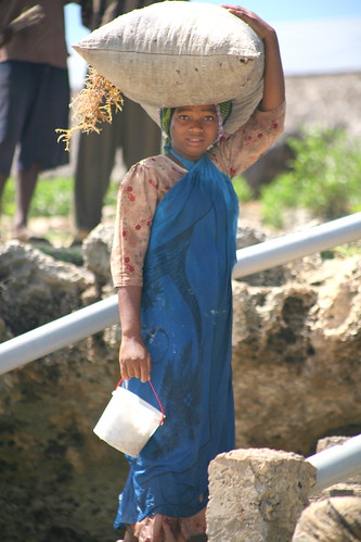 woman carrying a sack of seaweed on her head by the stairs