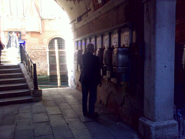 man looking for change next to olivetti store, piazza san marco. olivetti is now part of telecom italia