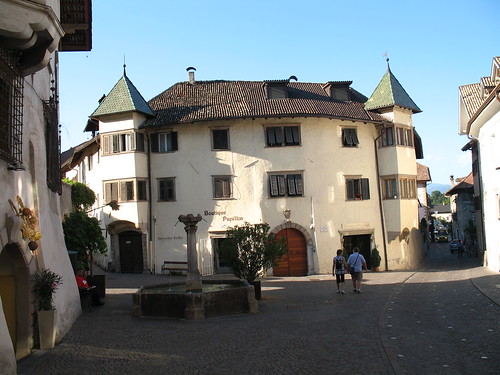 Steinbrunnen mit historischem Gebäude im Ortskern von Kaltern