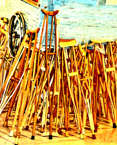 A large number of crutches of multiple sizes leaning against a wall