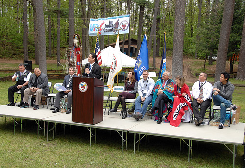 Robin Schepper, White House Let's Move! Executive Director, Assistant Secretary of Indian Affairs Larry Echo Hawk, Actor Chaske Spencer from the Twilight film series, White House official Charles Galbraith, and Tribal Leaders smile as Lyle Ignace, IHS Director for Improving Patient Care, takes the stage.