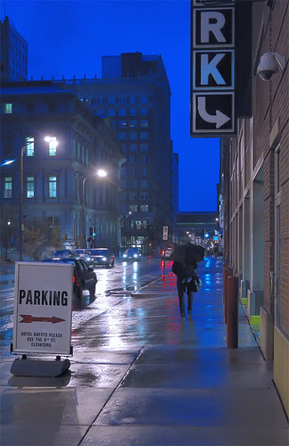 Parking sign, pedestrian with umbrella, in downtown Saint Louis, Missouri, USA - at dusk in the rain