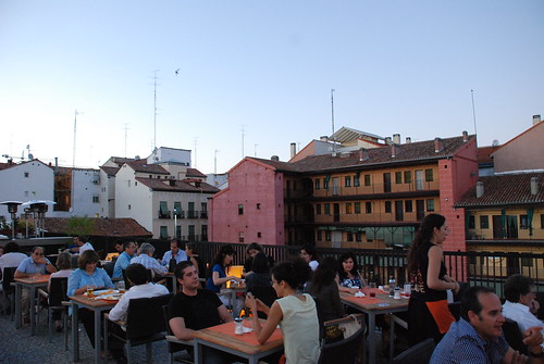 Gente charlando en un restaurante en una terraza con corralas de fondo