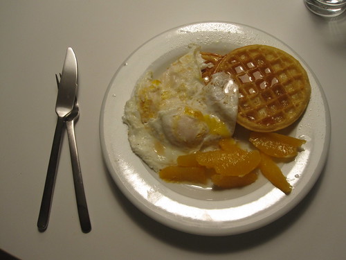 Waffles, orange and eggs with maple syrup