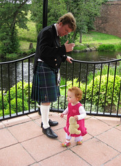 dad_baby_garden = Dad in a kilt watching Speck in the gazebo, with river and greenery in the background