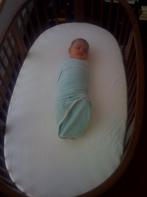 Laila swaddled and asleep in her new crib