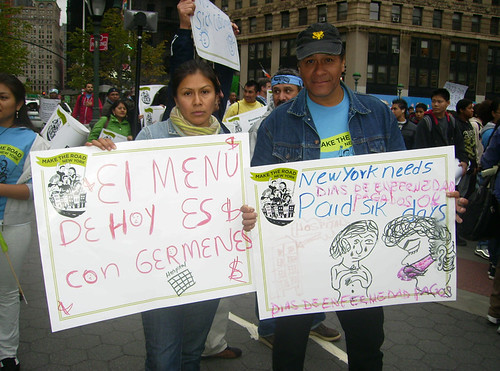 Todays menu is: Germs, reads a sign held by Gloria Gonzalez, standing with Gustavo Gomez, both Mexican immigrants.