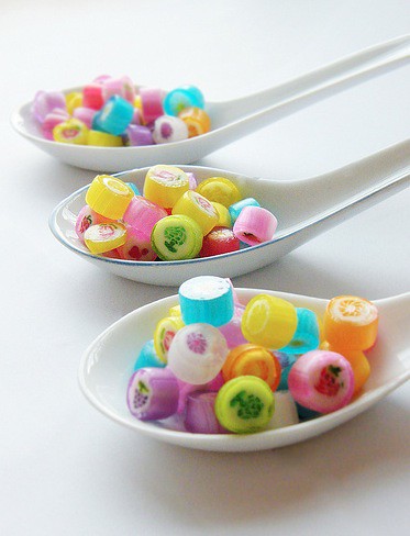 three  soup spoons are filled with brightly coloured Japanese rock candy.