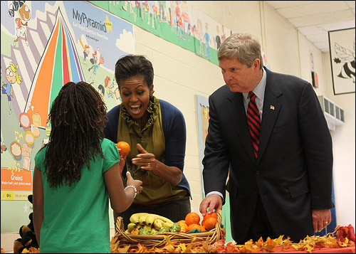 First Lady Michelle Obama and Secretary of Agriculture Tom Vilsack pass out fresh fruit to students at Hollin Meadows Elementary School