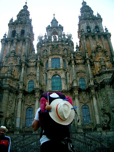 peregrina de espaldas mirando la catedral de Santiago de Compostela con la mochila a cuestas