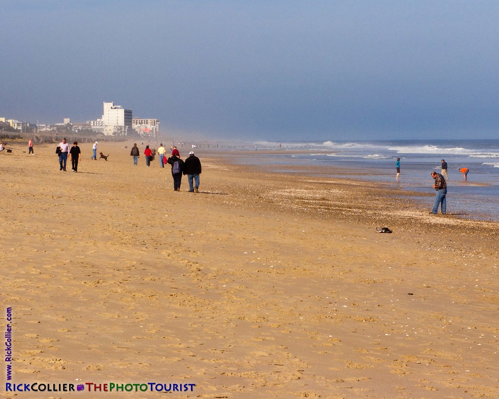 Walkers and beachcombers emerge to explore the widened beach as the sun finally emerges after a nor'easter clears out from Bethany Beach, Delaware, USA.