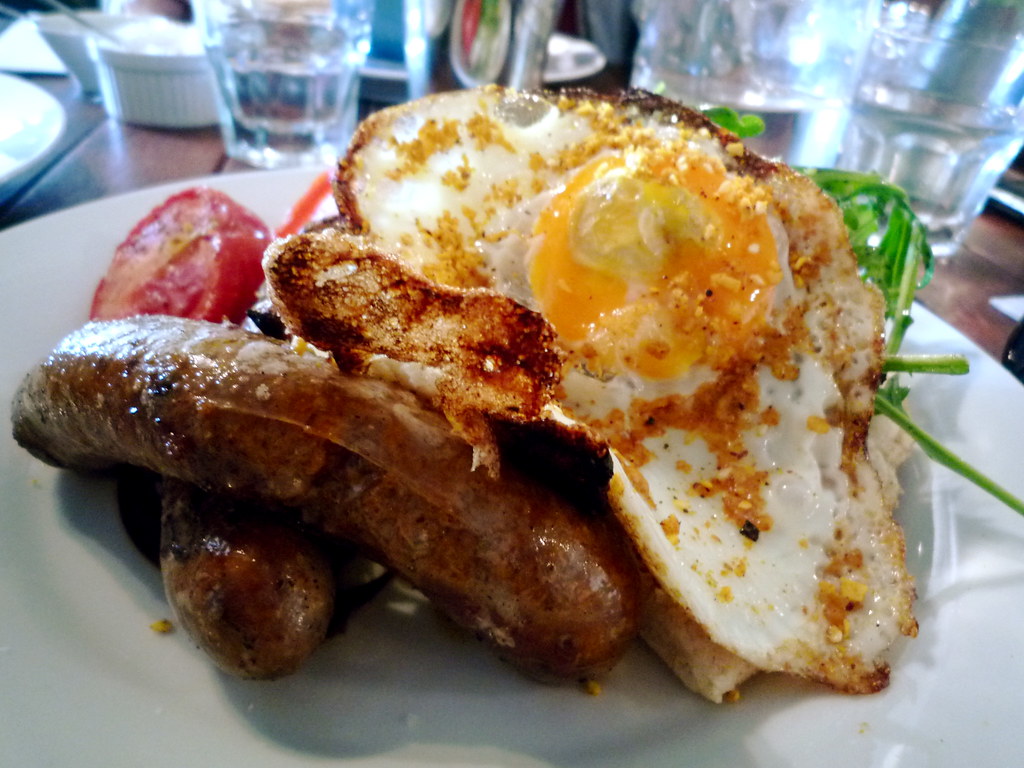 Dukkah spiced fried eggs with organic Merguez sausages, rocket, flat bread and roasted tomatoes