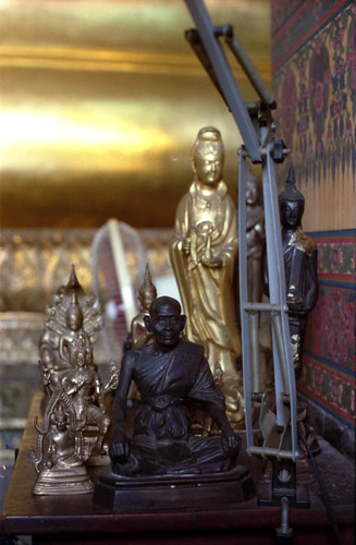 Buddha statues and monk statues, on a side table in a shrine, Bangkok, Thailand, in 1993 by Wonderlane
