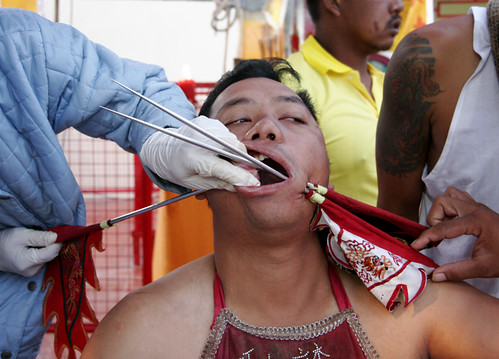 Man getting his cheek pierced at the Phuket Vegetarian festival