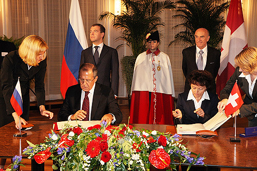 Dmitri Medwedew (Hintergrund), Sergei Lawrow und Eveline Widmer-Schlumpf unterzeichnen Staatsvertr
