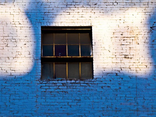 graffiti around a window: sky-blue painted brick, and a few white-painted clouds