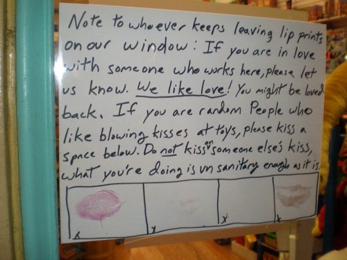 Note to whoever keeps leaving lip prints on our window: If you are in love with someone who works here, please let us know. We like love! You might be loved back. If you are random People who like blowing kisses at toys, please kiss a space below. Do not kiss on someone else's kiss, what you're doing is unsanitary enough as it is.