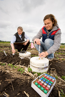 Using closed vented chambers, biological science aide Rochelle Jansen (right) and soil scientist Jane Johnson collect gas emissions from soil. Samples will be analyzed for carbon dioxide, nitrous oxide, and methane with a gas chromatograph.