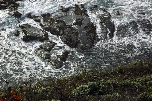 White swirls and pools, interesting shapes, over the cliff, Pacific Ocean waves splashing in on Swanton Black Finger Rocks, Pacific Ocean, North of Santa Cruz, California, USA by Wonderlane