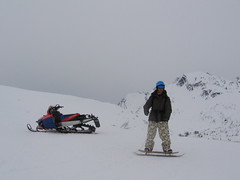 Marc ripping down gully one on the Ralston snowskate passing the parked sled.