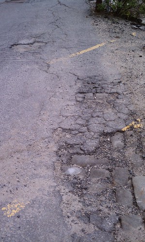 Cobblestones peeking thru the pavement by acornsfromelms