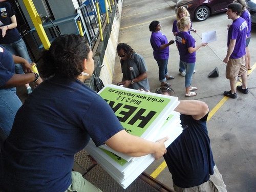 Volunteers from Kohl’s load signs that advertise USDA summer meals for kids into their cars at the loading dock of Wisconsin’s largest food bank.