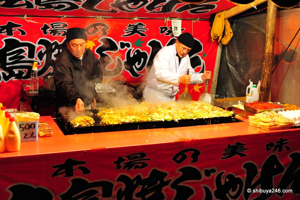 The Okonomiyaki chefs cook up a large hot plate full of food.