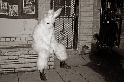 sad rabbit with combat boots sitting in front of a store by IntangibleArts